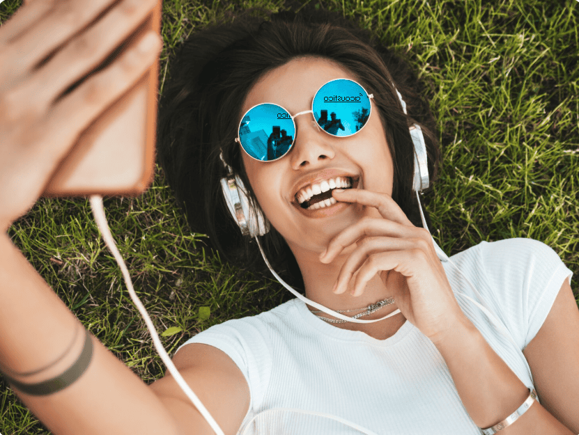 Jeune femme qui se relaxe dans l'herbe en écoutant de la musique 