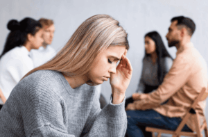 Jeune femme avec de l'hyperacousie se prenant la tête à cause des conversations derrière elle