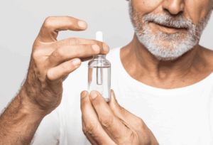 Homme qui tient un flacon de gouttes auriculaires