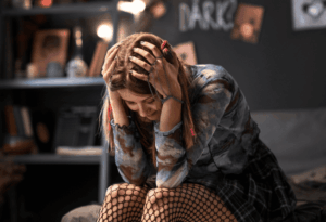 Jeune femme qui se prend la tête entre les mains et paraît dépressive