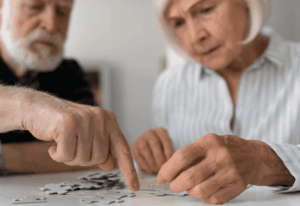 Deux personnes âgées occupées à faire un puzzle pour leur mémoire