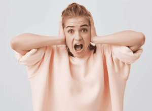 Jeune femme qui se bouche les oreilles en se demandant quels sont ces bruits dans les oreilles