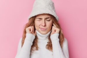 Femme qui se touche les oreilles à cause de l'acouphène
