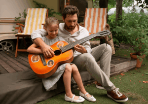 Père et sa fille jouant de la guitare, illustrant l'enrichissement sonore et une ambiance sonore apaisante.