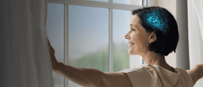 Femme ouvrant les rideaux illustrant l’approche BrainHearing d’Oticon