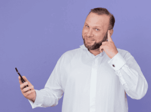 Homme souriant, téléphone à la main, prêt à prendre rendez-vous pour un bilan auditif.