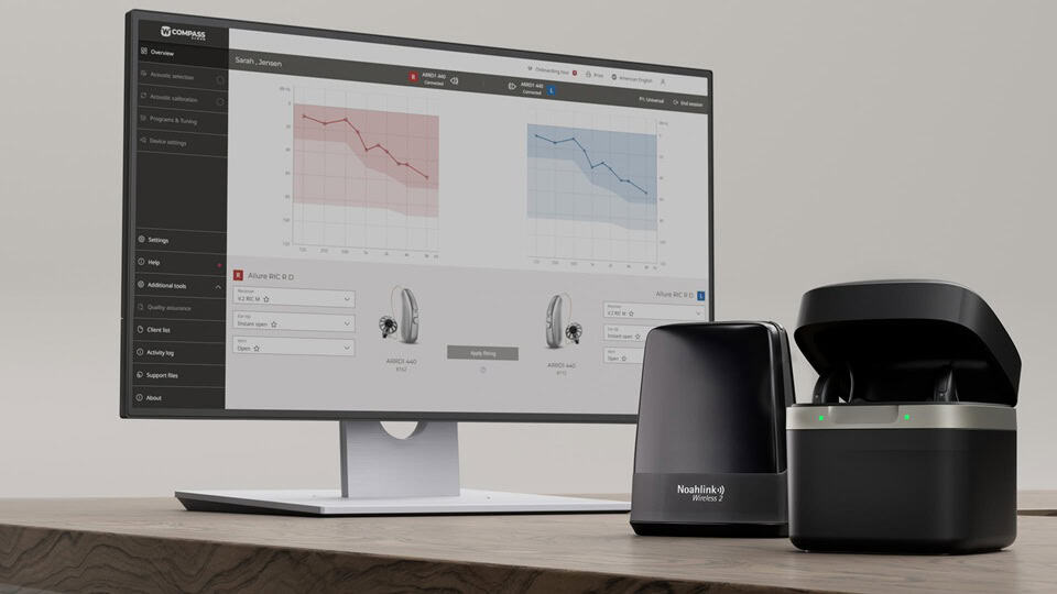Chargeur avec des Widex Allure RIC sur la table en face du logiciel de réglage