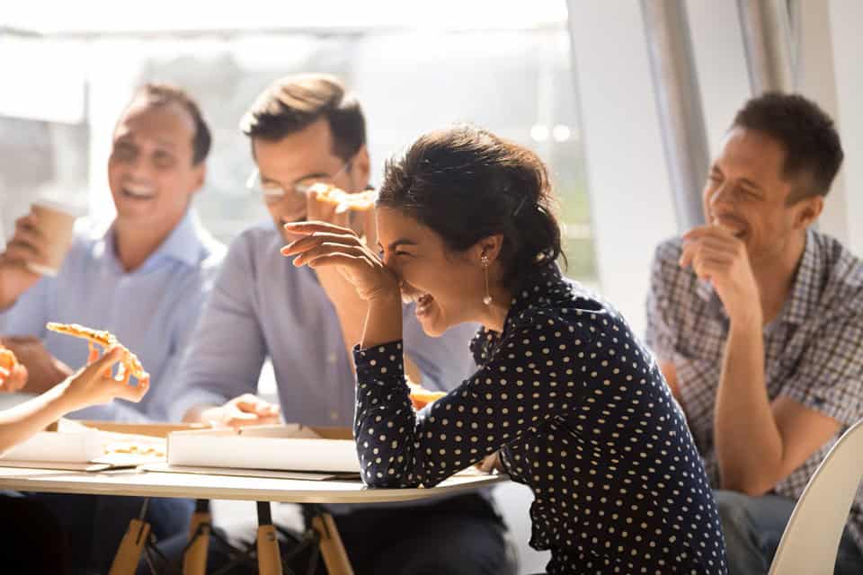 Femme échangeant avec ses collègues autour d'une pizza